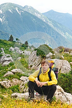 Young Man Traveller with backpack sitting on stones