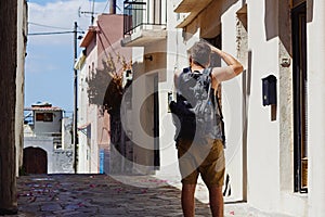 Traveller with camera and backpack takes pictures of the foreign city during the vacation, Crete, Greece