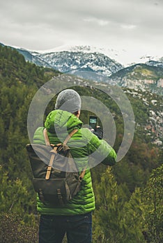 Young man traveller wearing bright clothes making photo of landscape