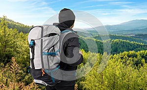 Young man trekking or hiking at sunny cold day on mountains with heavy backpack. Solo trekking or wanderlust adventure concept