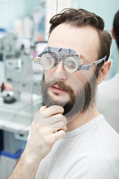 Young man with trial frames in ophthalmologist clinic
