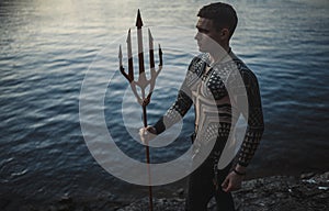 A young man with a trident against the background of water.