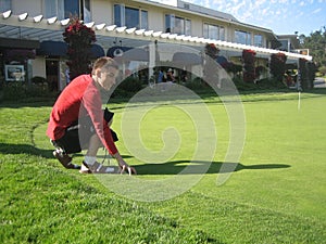 A young man tries to dense lawn grass on the golf
