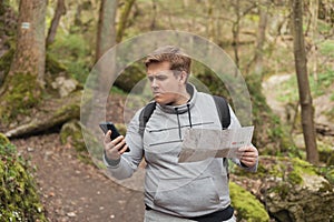 A young man tries to find a phone signal in the forest. Searching for mobile connection in wild nature on vacation