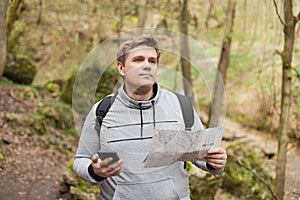 A young man tries to find a phone signal in the forest. Searching for mobile connection in wild nature on vacation