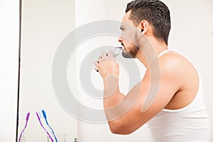 Young man trimming his beard in the bathroom