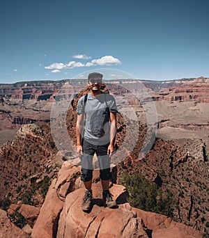 Young man trousist standing in front of Grand Canyon. Hiker with backpack enjoying view, USA. Travel and outdoort