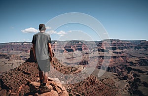 Young man trousist standing in front of Grand Canyon. Hiker with backpack enjoying view, USA. Travel and outdoort