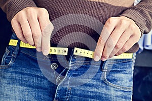 Young man trying to fasten his trousers