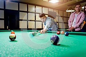 Young man trying to hit the ball in billiard.