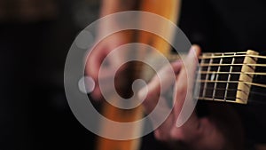 A young man tunes an acoustic guitar plucking the strings and musical notes