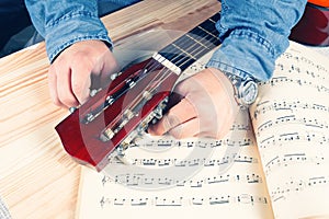 Young man tuning a guitar.