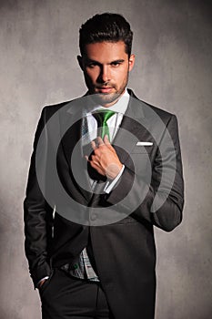 Young man in tuxedo coat fixing his green tie