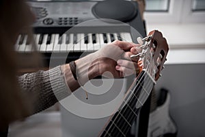 Young man twisting guitar pads for adjusting strings