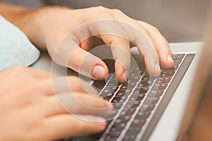 Young man typing on a laptop keyboard. Close-up details. Man`s hands.  Working online. Freelance concept.