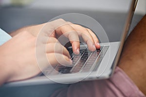 Young man typing on a laptop keyboard. Close-up details. Man`s hands.  Working online. Freelance concept.
