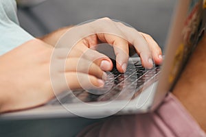 Young man typing on a laptop keyboard. Close-up details. Man`s hands.  Working online. Freelance concept.