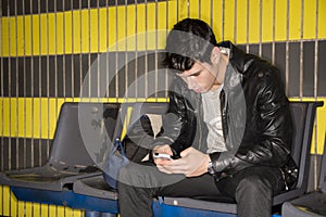 Young man typing on smartphone waiting for subway train