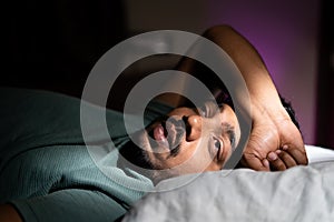 young man unable to sleep during night at bedroom - concept of suffering from insomnia, thoughtful and problems