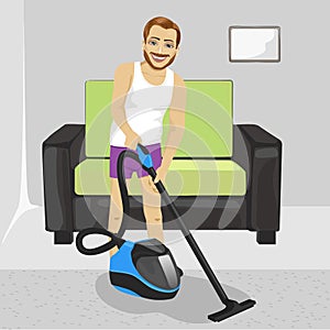 Young man in underwear cleaning carpet with vacuum cleaner at home