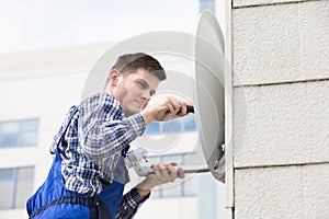 Man Fitting TV Satellite Dish On Wall