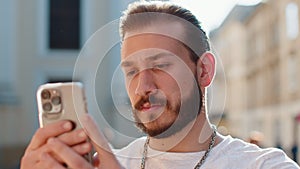 Young man use smartphone typing text messages browsing internet finishing work looking at camera
