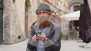 Young man use smartphone typing text messages browsing internet finishing work looking at camera