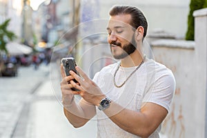 Young man use smartphone typing text messages browsing internet finishing work looking at camera