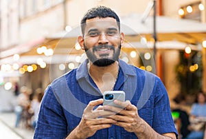 Young man use smartphone typing text messages browsing internet finishing work looking at camera