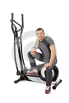 Young man uses elliptical cross trainer.