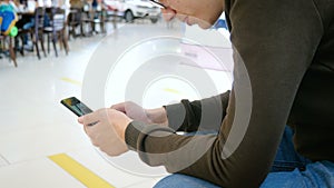 A young man uses a mobile phone in a shopping center.