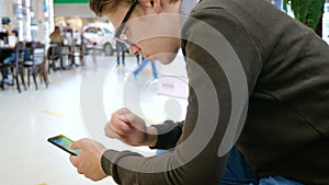 A young man uses a mobile phone in a shopping center.