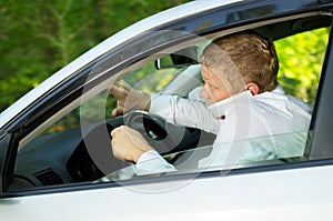 Young man uses the phone behind the wheel of a car