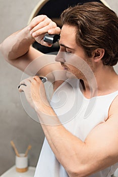 young man using antiperspirant stick on