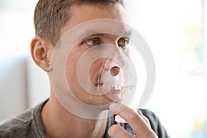 Young man using asthma machine indoors