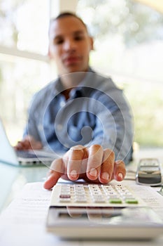 Young Man On Using Calculator At Home