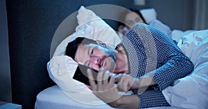 Young Man Using Cellphone While Her Wife Sitting On Bed