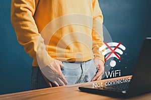 Young man using a computer laptop to connect to wifi in his home but wifi not connected.