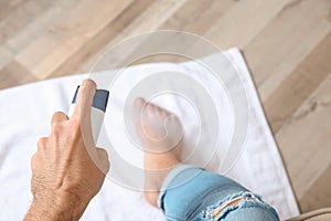 Young man using deodorant for feet at home