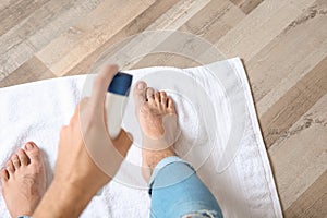 Young man using deodorant for feet at home