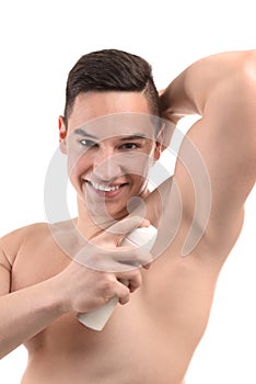 Young man using deodorant on white background