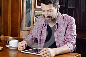 Young man using digital tablet at a cafe.