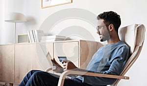 Young man using digital tablet with credit card at home. Businessman or entrepreneur working. Online shopping concept