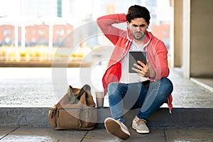 Young man using digital tablet outdoors.