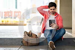 Young man using digital tablet outdoors.