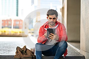 Young man using digital tablet outdoors.