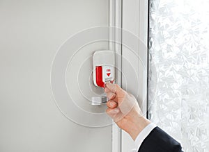 Young man using fire alarm system indoors