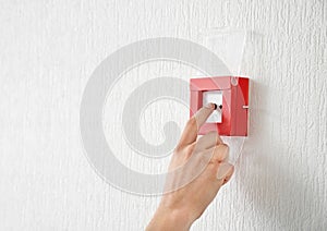 Young man using fire alarm system indoors