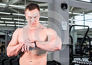Young man using fitness bracelet during sports training in the gym