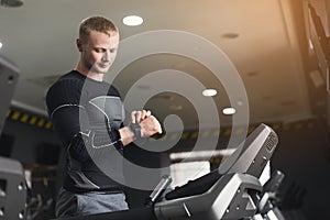 Young man using fitness tracker in gym